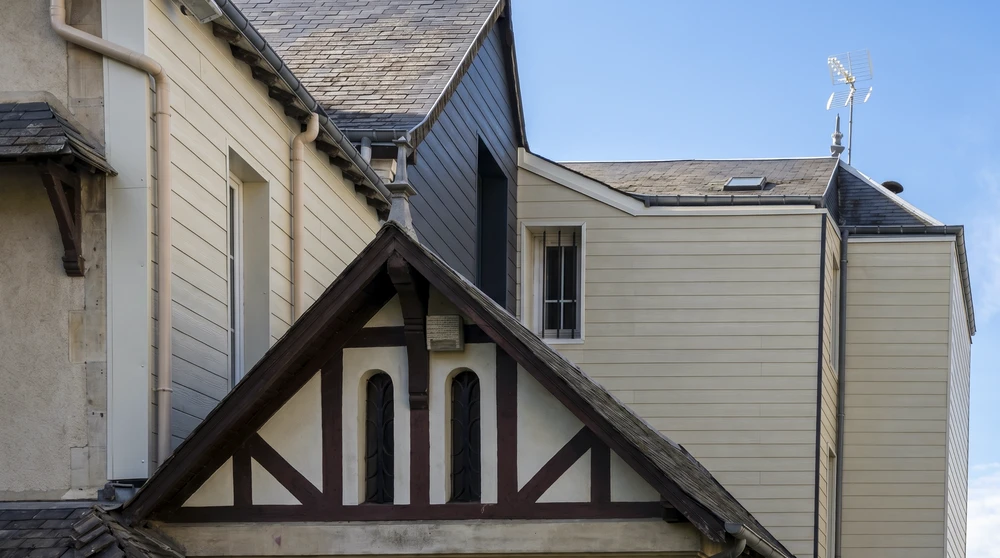 Ouvriers en équipement de sécurité installant une toiture métallique sur bâtiment industriel