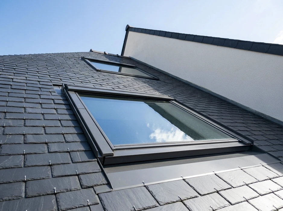 Gros plan sur des mains d'ouvriers installant des tuiles de toit en céramique jaune montées sur des planches en bois recouvrant un toit de bâtiment résidentiel en construction